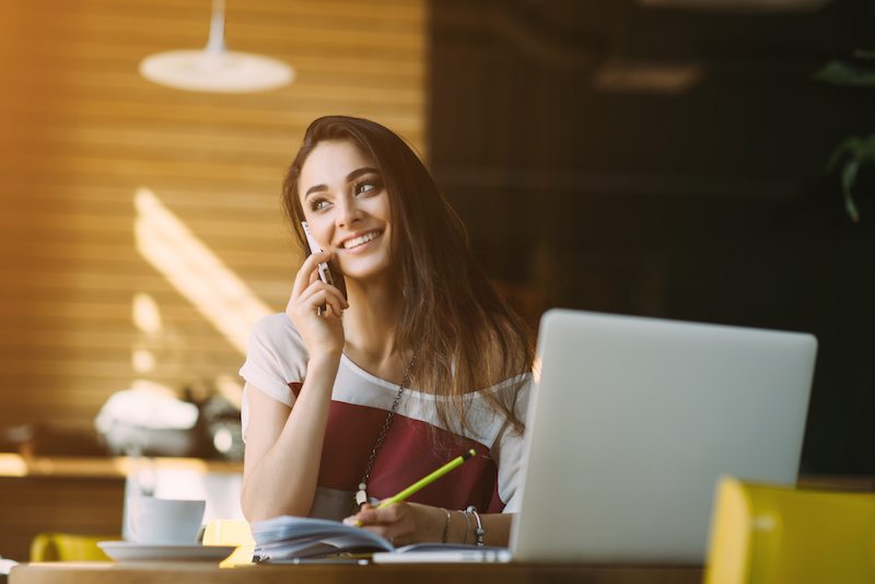 woman talking on phone in front of laptop