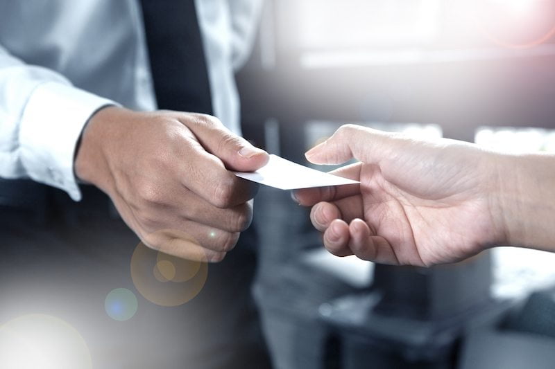 Man handing paper pamphlet to another person